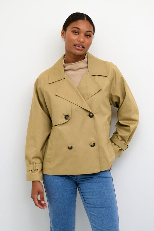 The Elise jacket from Scandi brand Kaffe is a stylish trench coat that is cut at the hips. It is double-breasted with a notch lapel and a storm flap on the right side. The jacket has long raglan sleeves with adjustable sleeve tabs at the edge. The fit of the jacket is relaxed and it has vertical front pockets.