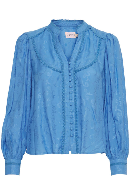 A stunning pretty blue blouse from our favourite Scandi brand Atelier Reve. A beautiful embossed fabric with the softest feel. A stylish notch neck with a mandarin collar. Covered buttons to fasten. Long sleeves with two buttons at the cuff. There is a delicate lace trim on the front and on the cuffs.