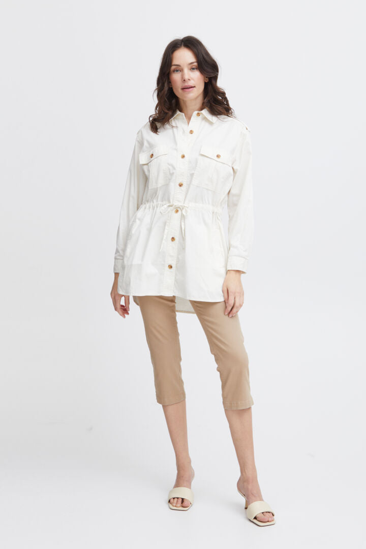 Long length safari style shirt from Scandi brand Fransa. This great neutral piece has a standard size collar and long sleeves. The cuff has a single button to fasten. The shoulder has an elegant epaulette with button trim. There is a drawstring waist to cinch in and there are two breast pockets on the front. A great neutral piece.