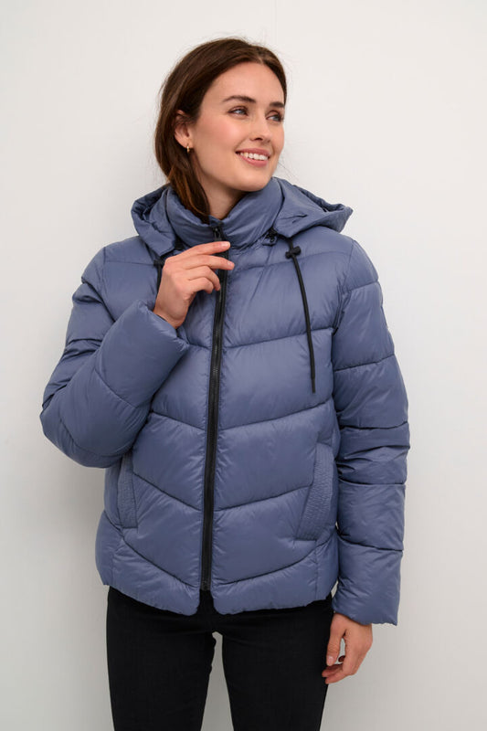 The KAsusanne puffa style jacket from Danish brand KAFFE is a shorter length puffa. It covers the bottom and has a detachable hood with pull ties. The sleeves have an internal cuff. It has slanted side pockets and is a great piece for the transition from Autumn to Winter. The fit is true to size.