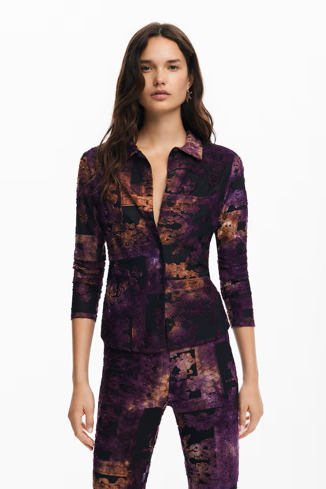 The fabulous Nebula shirt from Spanish brand Desigual ia a beauty. This classic shirt shaped top is in a super stretch fabric with a collar and button front. The quirky print is on a black background and includes natural shades and vibrant purple tones. The fabric is textured and the long sleeves have no cuff. The fit is true to size.