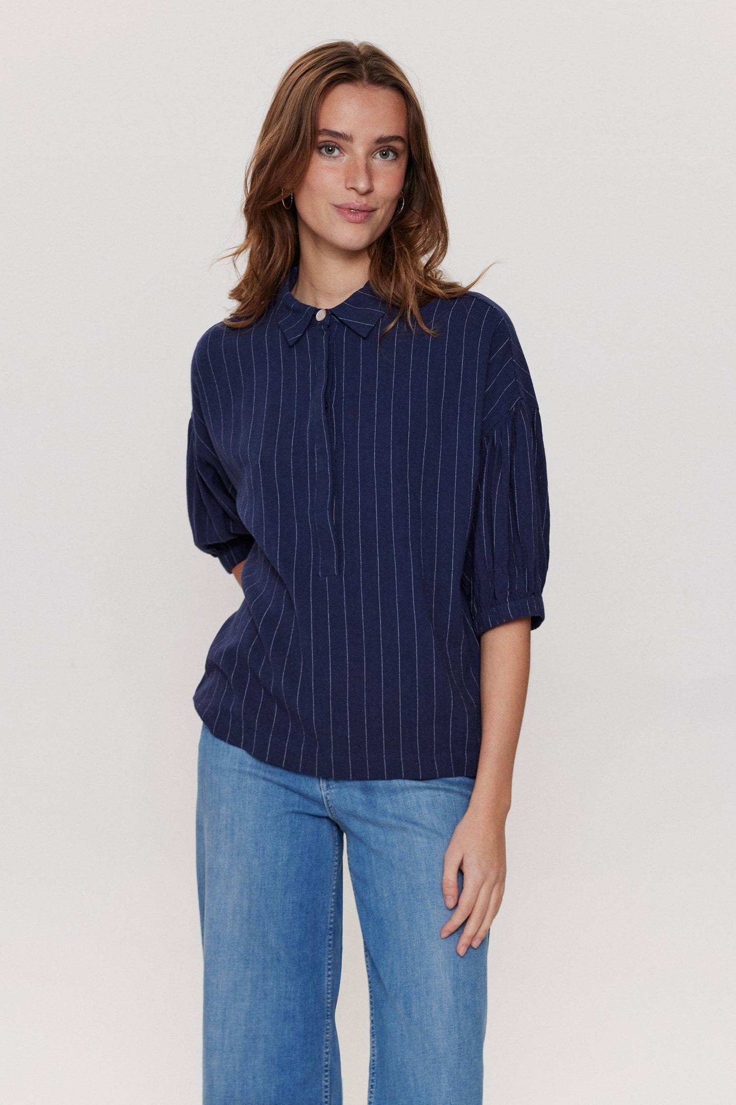 Another great piece by Scandi brand Numph. This casual style shirt in navy pin stripe is super cool. It has a simple shirt collar and concealed buttons to close from the neck to three quarters down the front . There is a single contrasting button at the neck. The sleeves are short a slightly puffed with an elasticated cuff . The fit is generous. Matching trouser available.