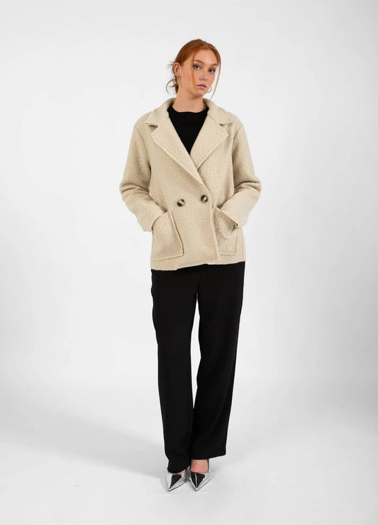 Add warmth and style to your wardrobe with this beige bouclé jacket from CC HEART. It's soft bouclé texture and modern design make it ideal for cooler days. Double breasted with two front pockets. The fit is true to size.